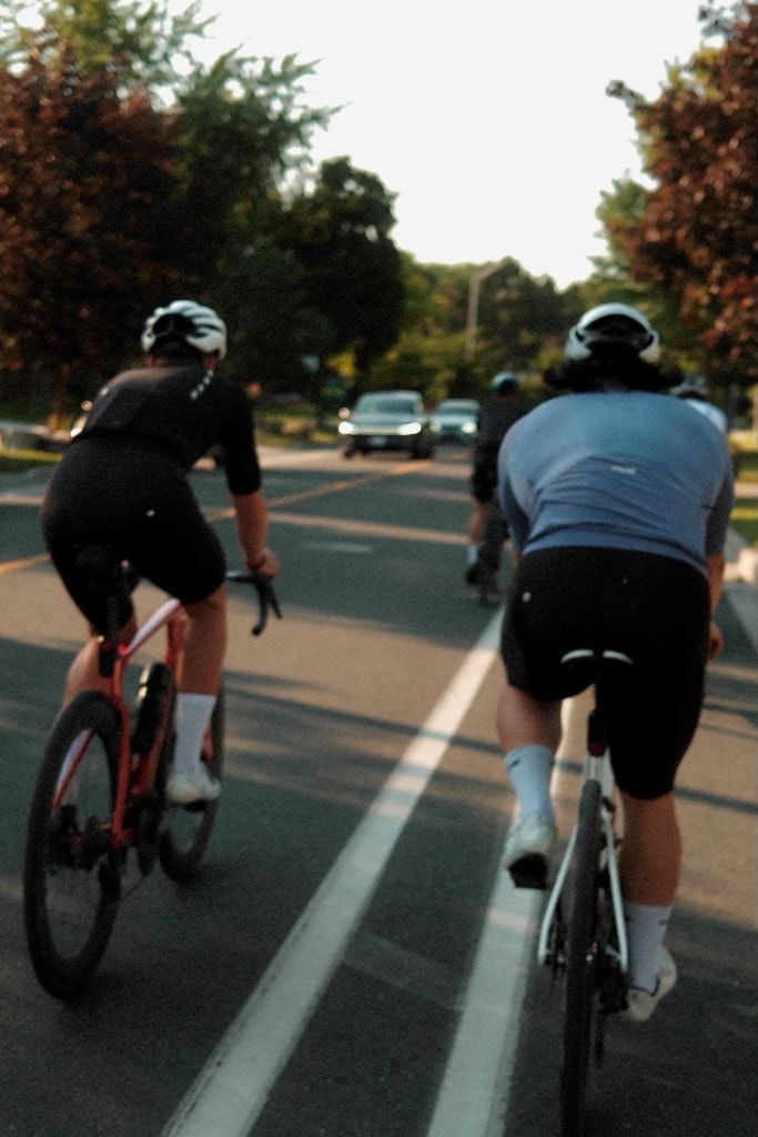 Following a small group of riders down a shaded road